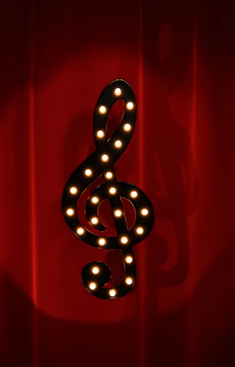Best of Musicals. Dekorativ bild med G-klav mot fördragen ridå.