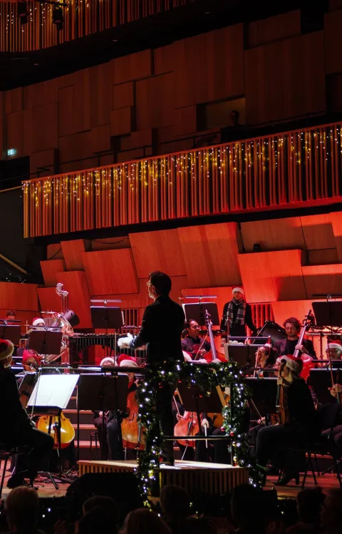 Konsertbild från en julkonsert, med julklädd orkester och kör