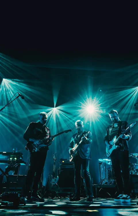 Personer på en scen med blått ljust bakom dem 