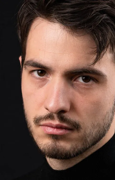 Person med svart skjorta står framför en svart bakgrund