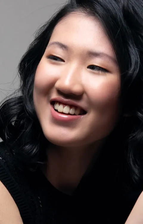 Kvinna med mörkt hår som ler mjukt åt sidan