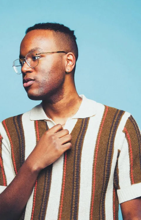 Person med randig t-shirt tittar åt sidan framför en blå bakgrund