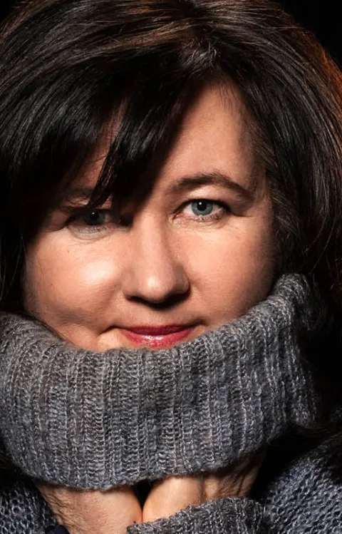 Person klädd i en varm, stickad tröja mot mörk bakgrund, omgiven av grafiska linjeillustrationer.