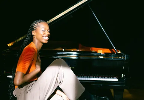 Leende flicka framför en mörk bakgrund till konserten Beethoven och Sjostakovitj med Malmö Symfoniorkester.