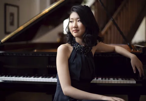Pianisten Sophia Liu sitter vid en flygel och tittar till vänster ut ur bild.
