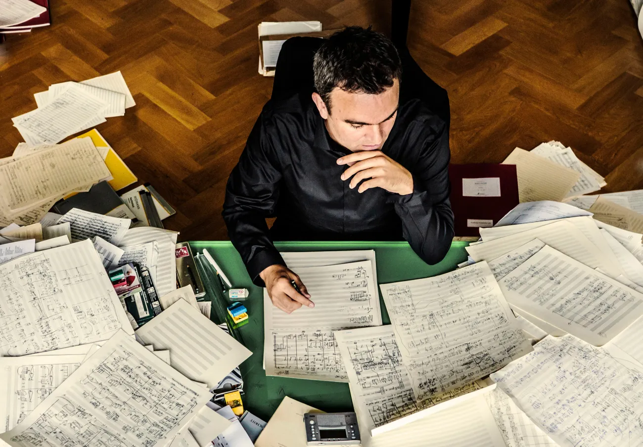 Jörg Widmann i sitt arbetsrum omgiven av notpapper
