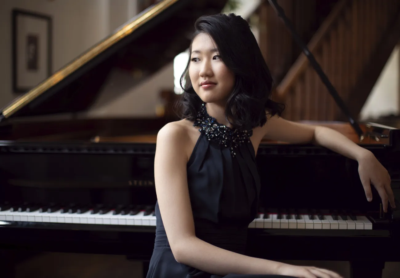 Pianisten Sophia Liu sitter vid en flygel och tittar till vänster ut ur bild.