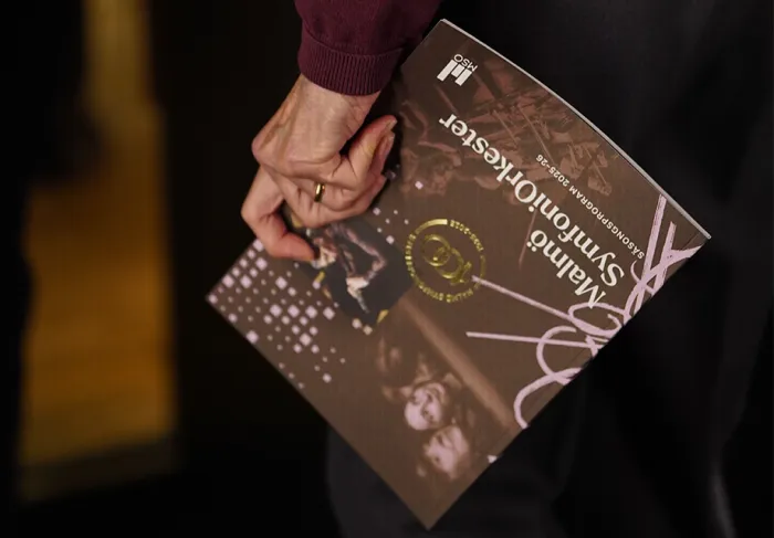 En hand som håller i säsongskatalogen 2025–26
